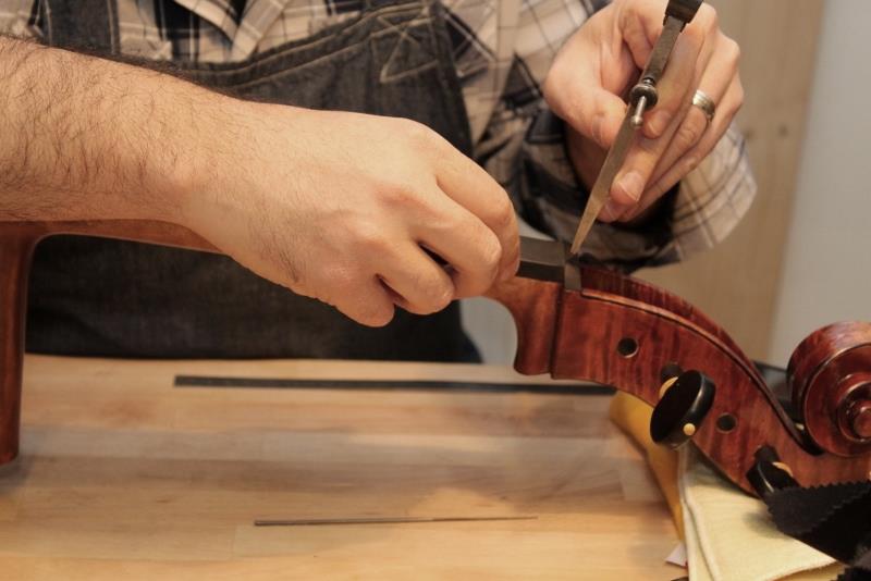 Geigenbauer richtet ein Streichinstrument in der Werkstatt ein